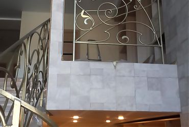 Лестница бетонная обшитая дубом с кованым ограждением - Отрадное